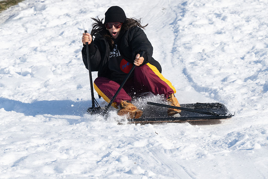 A person uses a card table as a makeshift sled to go sledding