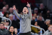 basketball coach on sideline with hands in the air pointing