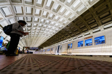 view from floor of metro station with people waiting as train pulls up