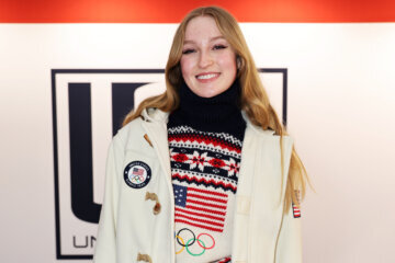 woman in olympic jacket and usa sweater at olympic welcome event smiling