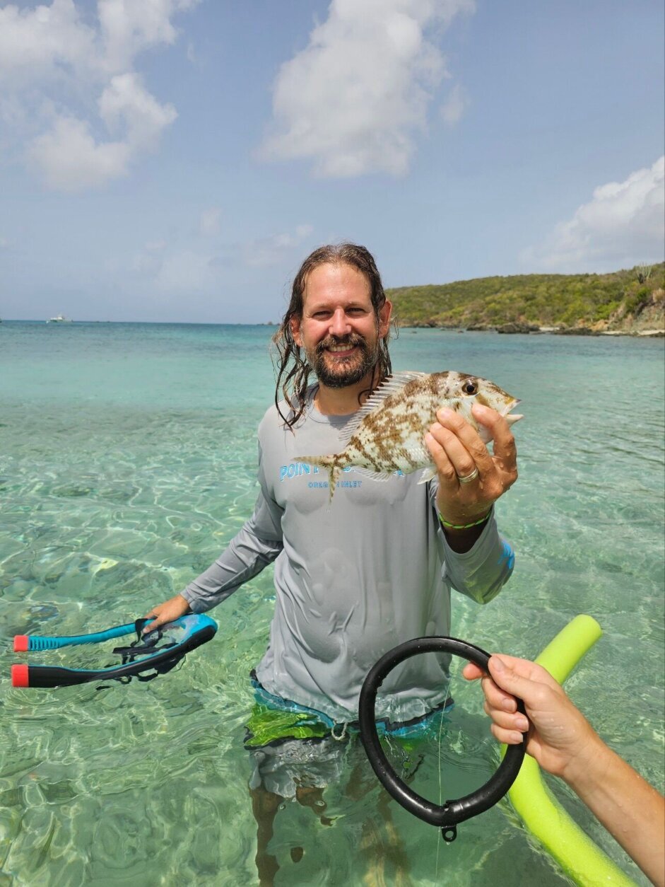 man standing in ocean holding fish