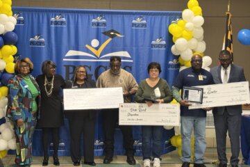 PGCPS officials and honorees hold up giant checks