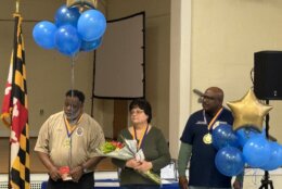 Three honorees holding balloons and a bouquet of flowers