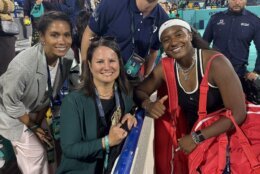 tennis player on right posing for picture with members of crowd on left