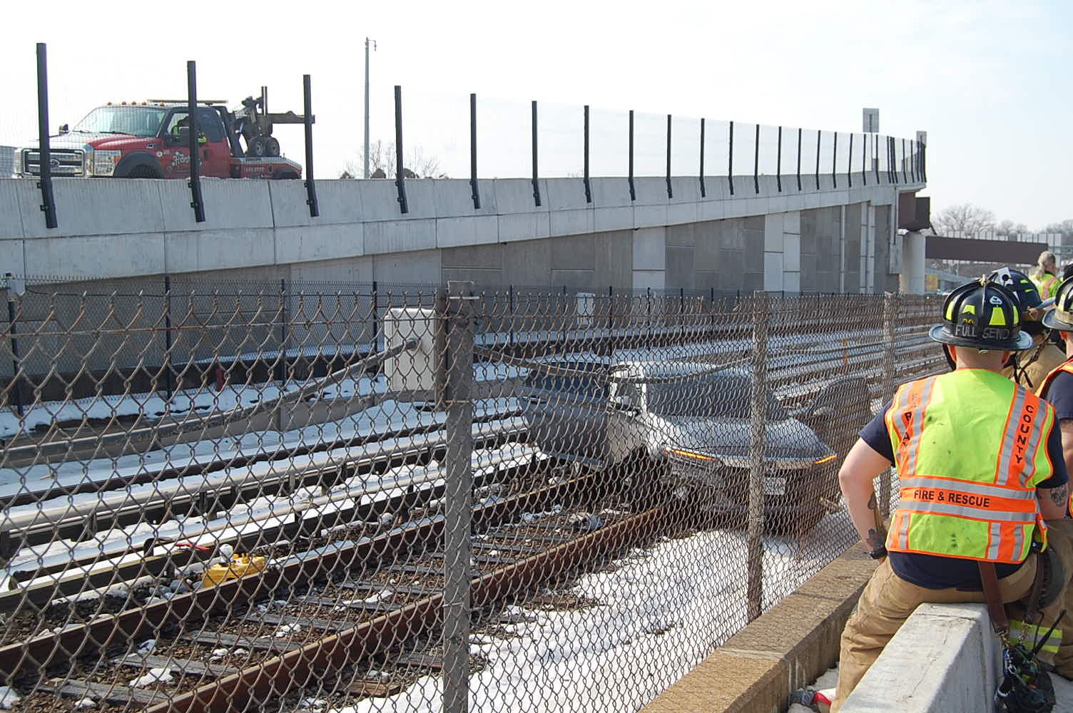 car seen through fencing sitting on metro train tracks