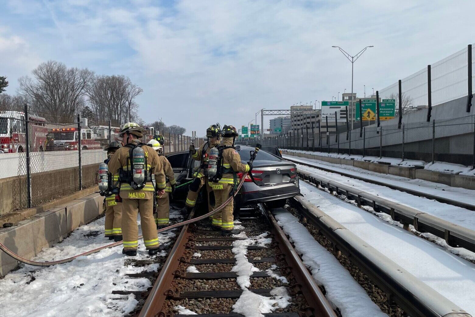 firefighters standing near a car on Metro train tracks