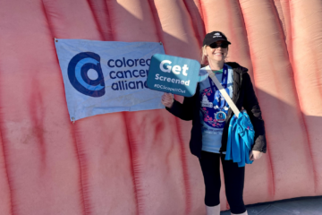 woman holding a sign in front of a pink foam tunnel