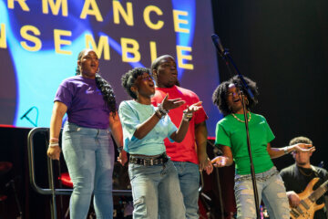 a group of people sing on stage