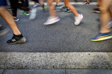 People from the knees down running on pavement