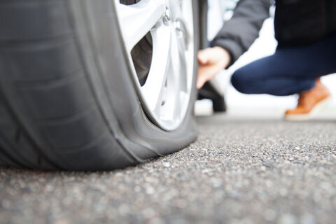 Man touching a flat tire on the roadside