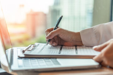 Hand holding a pen writing on paper.