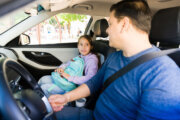 Father in driver's seat talking to young girl in passenger's seat.