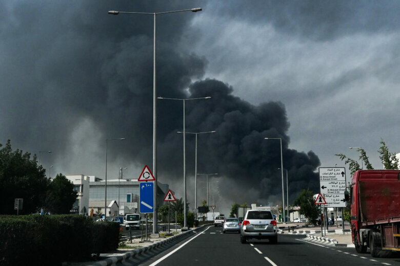plume of black smoke rises in sky in middle eastern city