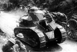 Two soldiers are passed by tanks