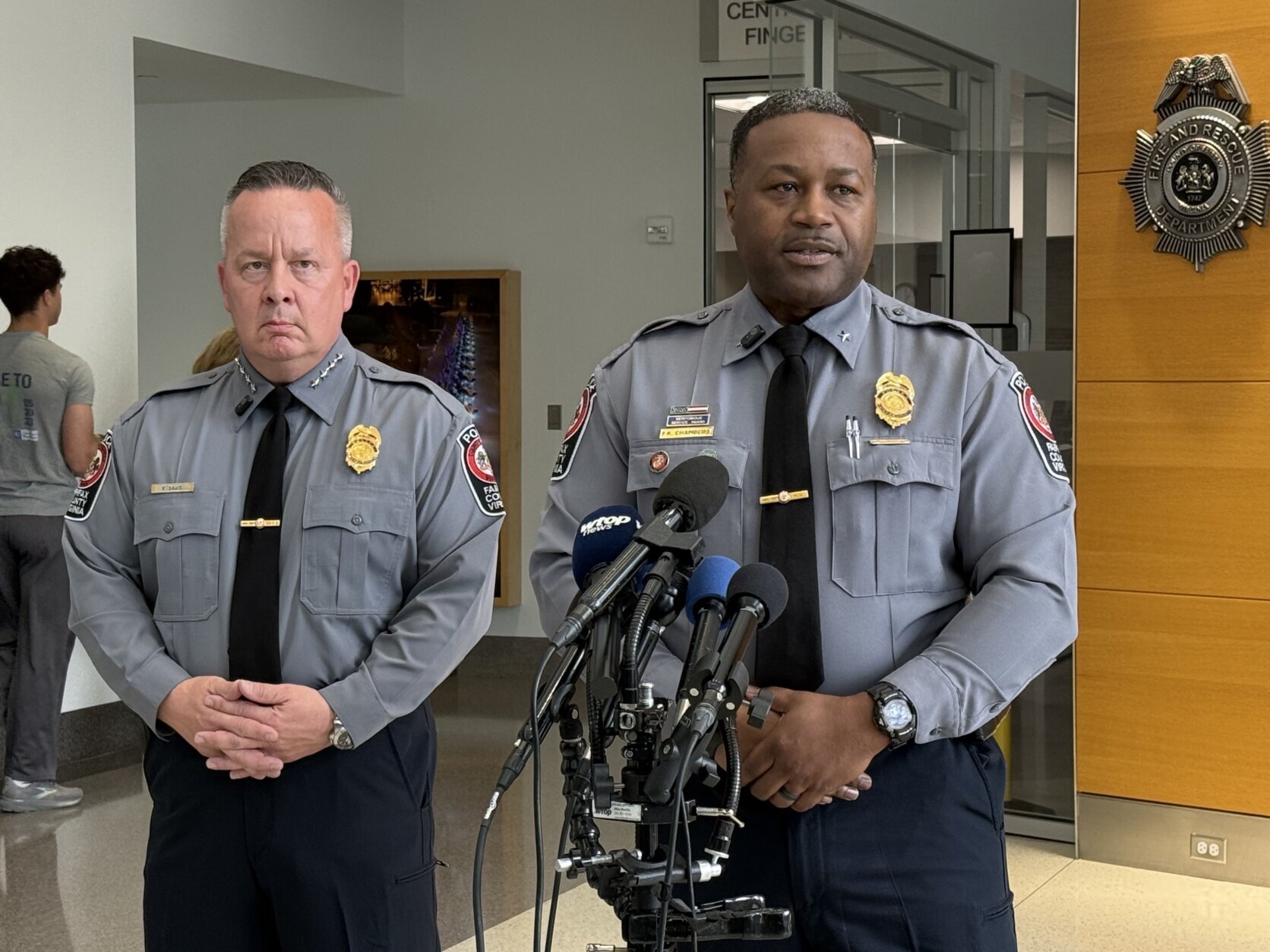 two police officers speak behind microphones