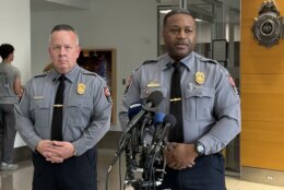 two police officers speak behind microphones