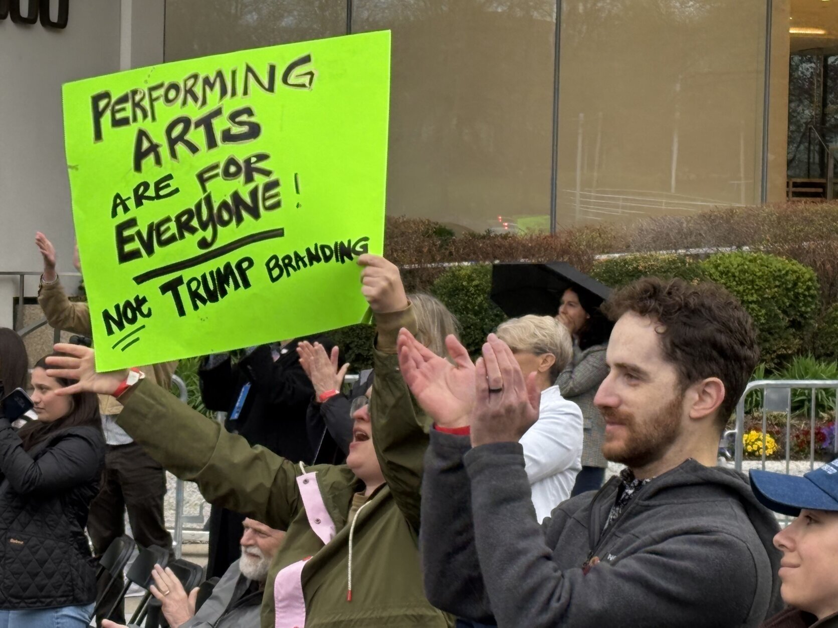 A demonstrator holds a sign that says "Performing arts are for everyone! Not Trump branding"