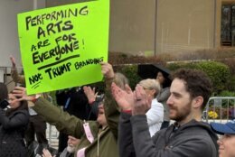 A demonstrator holds a sign that says "Performing arts are for everyone! Not Trump branding"