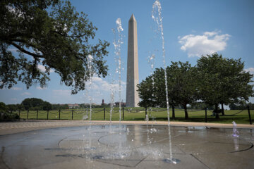 A fountain in front of the Washington Monument sprays water on the National Mal
