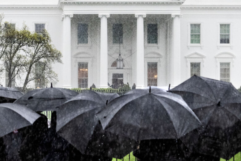 People hold umbrellas in the rain in front of the White House in Washington, DC, on April 3, 2024. (Photo by Jim WATSON / AFP) (Photo by JIM WATSON/AFP via Getty Images)