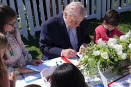 President Donald Trump sits down with children as he participates in the White House Easter Egg Roll on the South Lawn