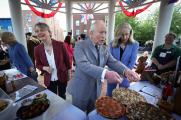 Britains King Charles III, accompanied by Virginia Governor Abigail Spanberger, right, speaks with employees of Melting Pot Pizza