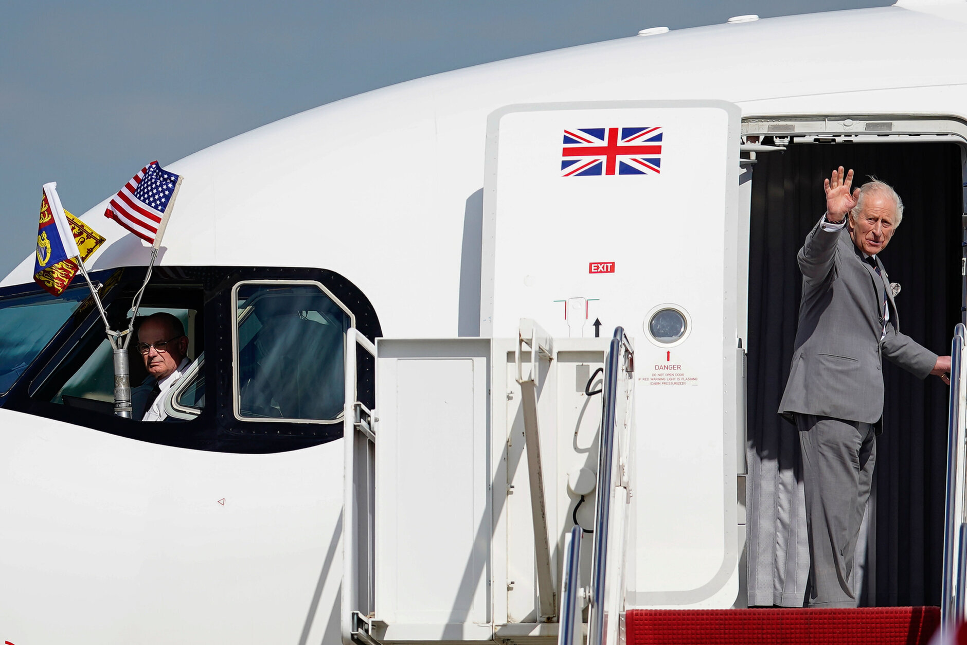 Britain's King Charles III waves as he boards his plane to depart at Joint Base Andrews, Maryland,