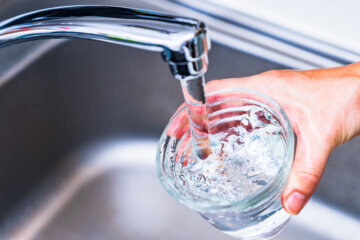 woman hand holding cup under running sink