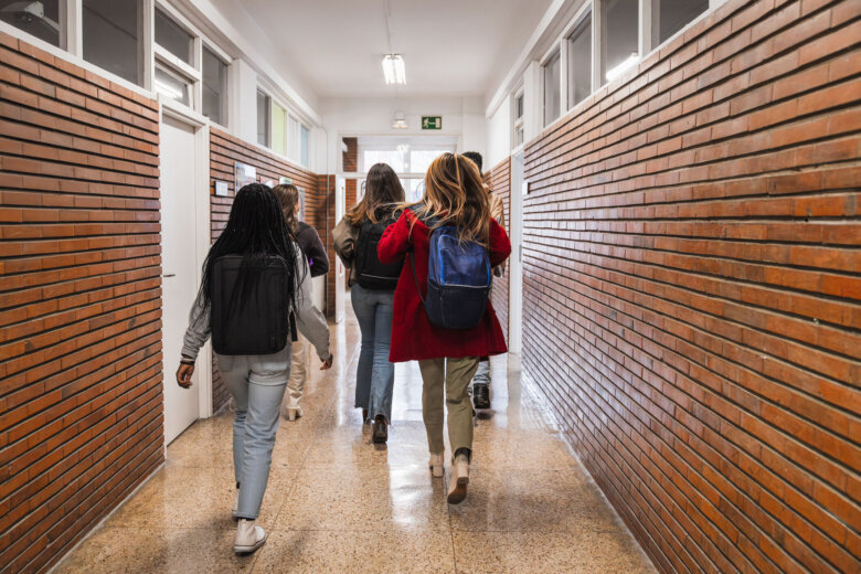 Group of students walking together down a bustling school hallway.