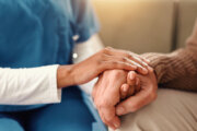 Holding hands, closeup and senior person with nurse on sofa for comfort, empathy and support. Retirement home, healthcare and caregiver with patient for care, help and compassion in assisted living