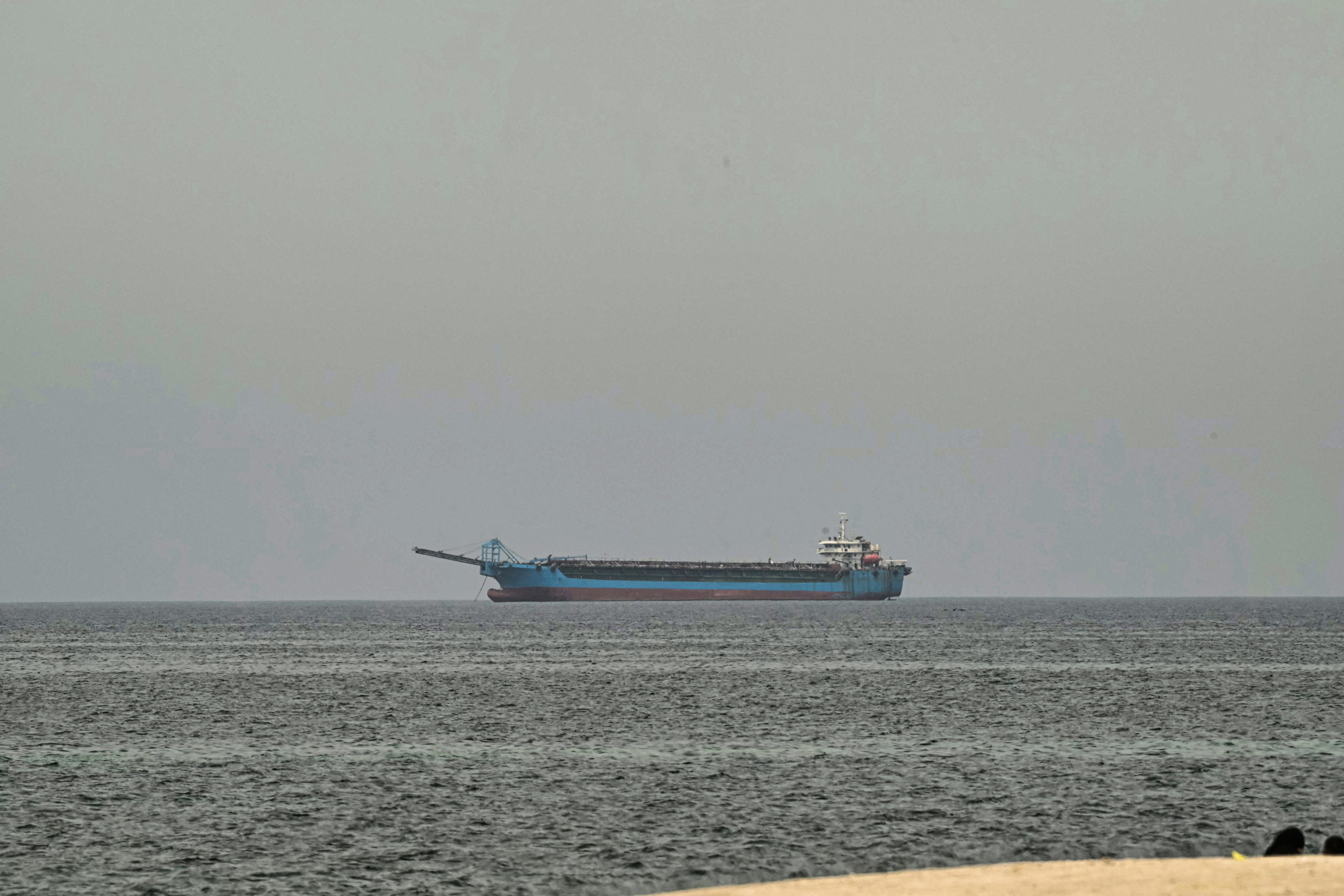 A ship on the horizon between a gray sky and darker gray waters