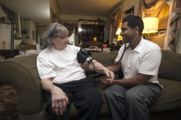 Doctor doing a homevisit examines a woman.