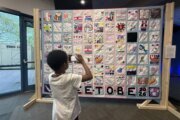 a child takes a photo of a hanging quilt