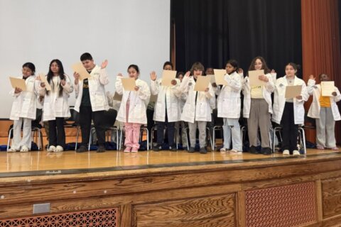 Howard University students help 4th and 5th graders trade bookbags for white coats