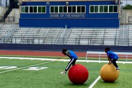 students running a drill with large colorful balls