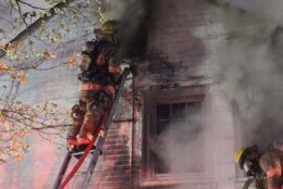 firefighter on ladder of home with smoke