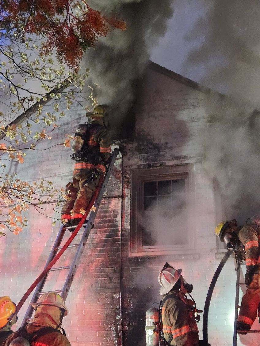 firefighter on ladder of home with smoke