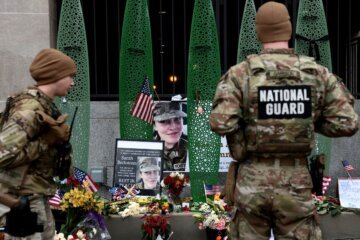 National Guard soldiers from Alabama look at a makeshift memorial honoring West Virginia National Guard soldier Sarah Beckstrom, on December 2, 2025. Beckstrom died after being shot outside a subway station in Washington, DC, in an attack that injured one other member of the National Guard.