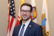 portrait shot of man standing in front of flags wearing suit