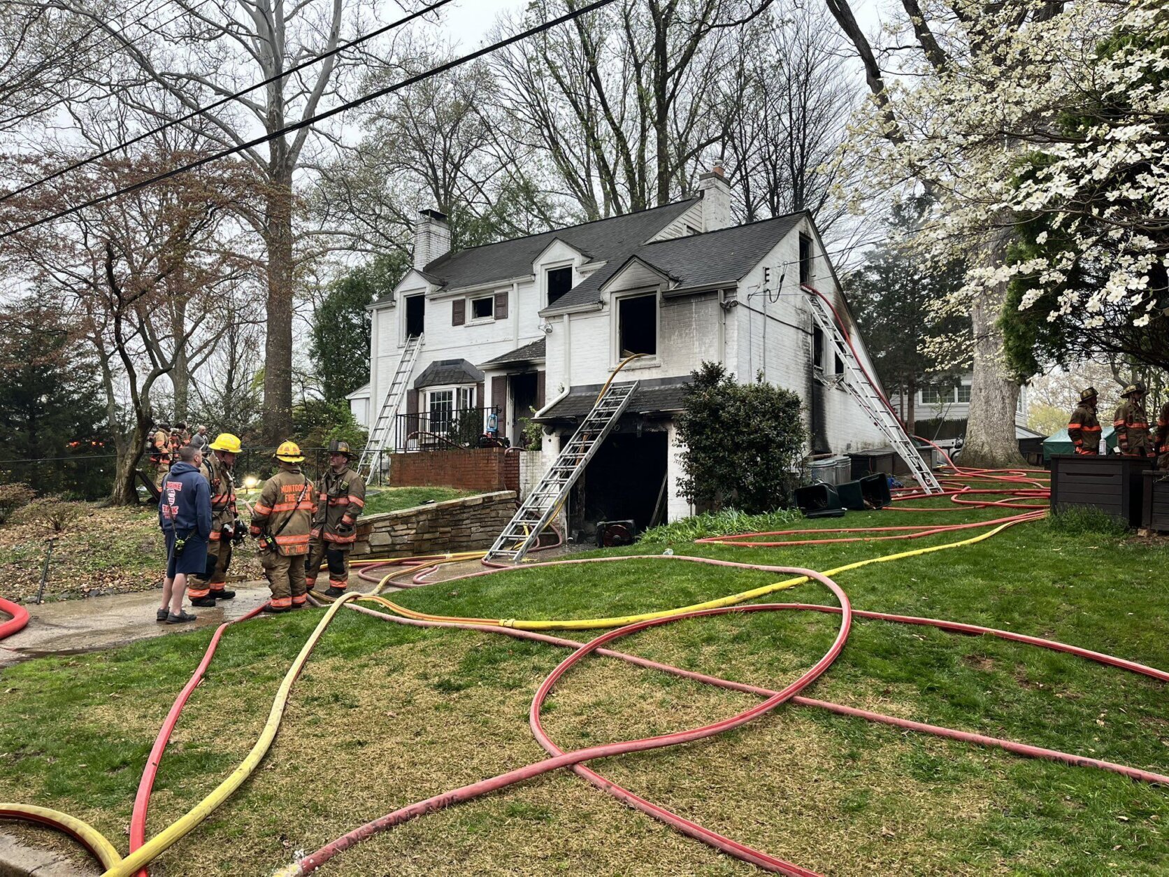 firefighters outside house with hoses after fire