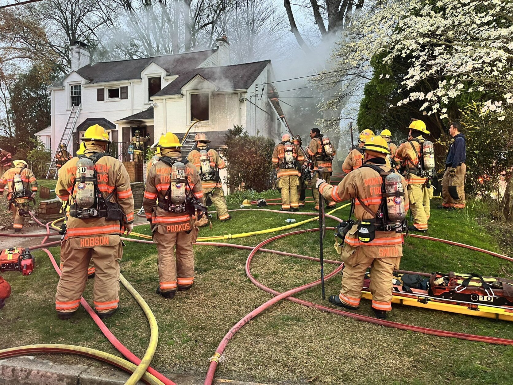 firefighters outside of house responding to fire, smoke coming from home