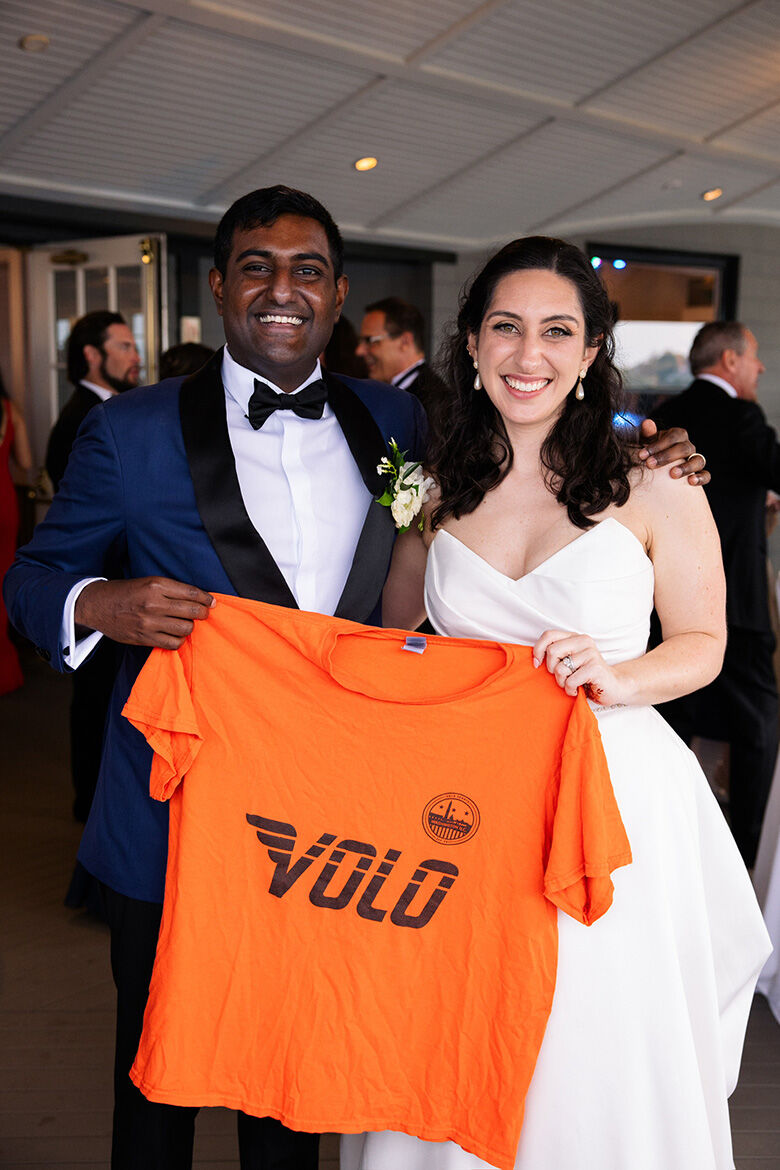 Brittany Keroack, 32, and Shank Subramani, in wedding attire holding up a Volo t-shirt