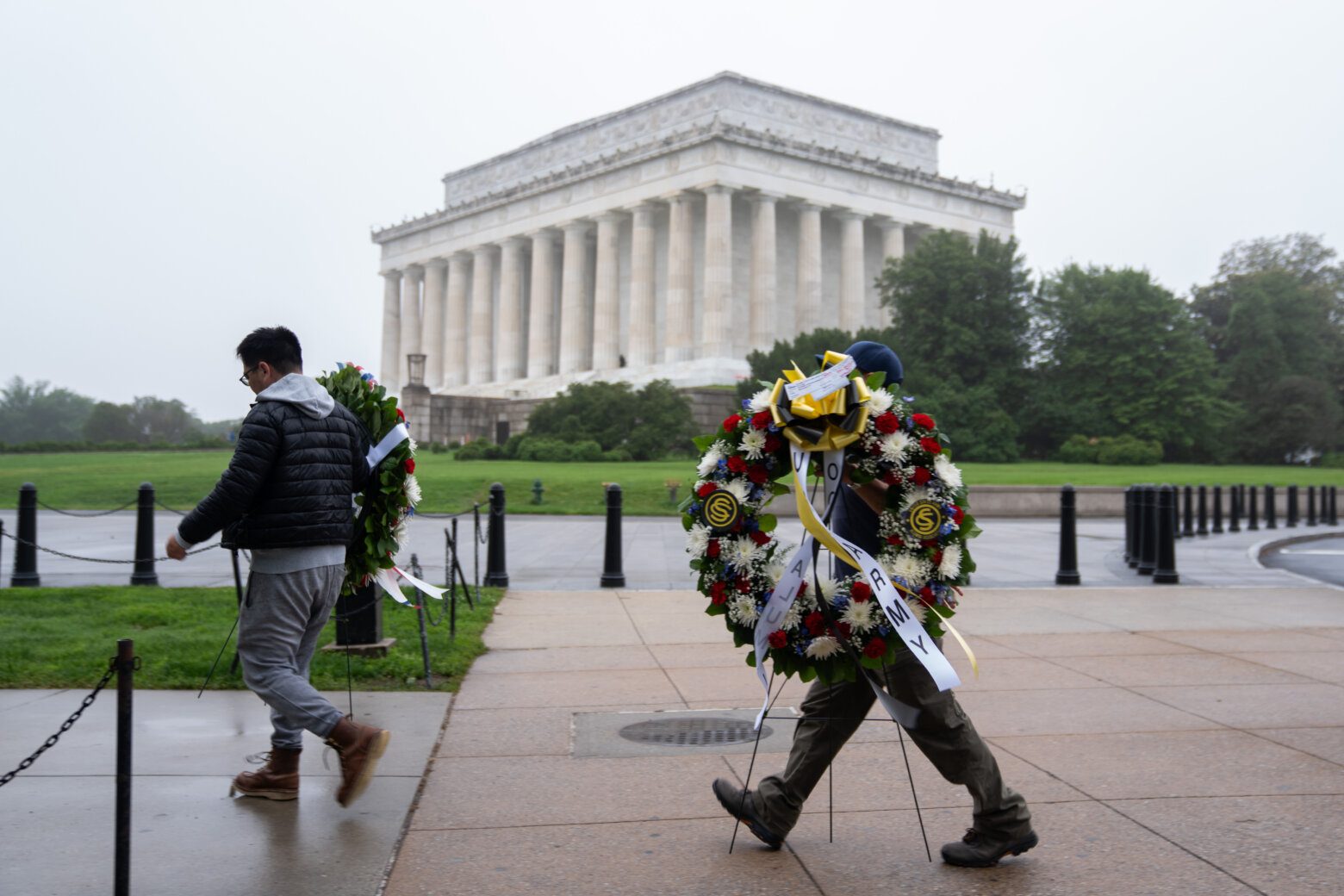 Individuals carry commemorative wreaths to place at the Vietnam Veterans Memorial