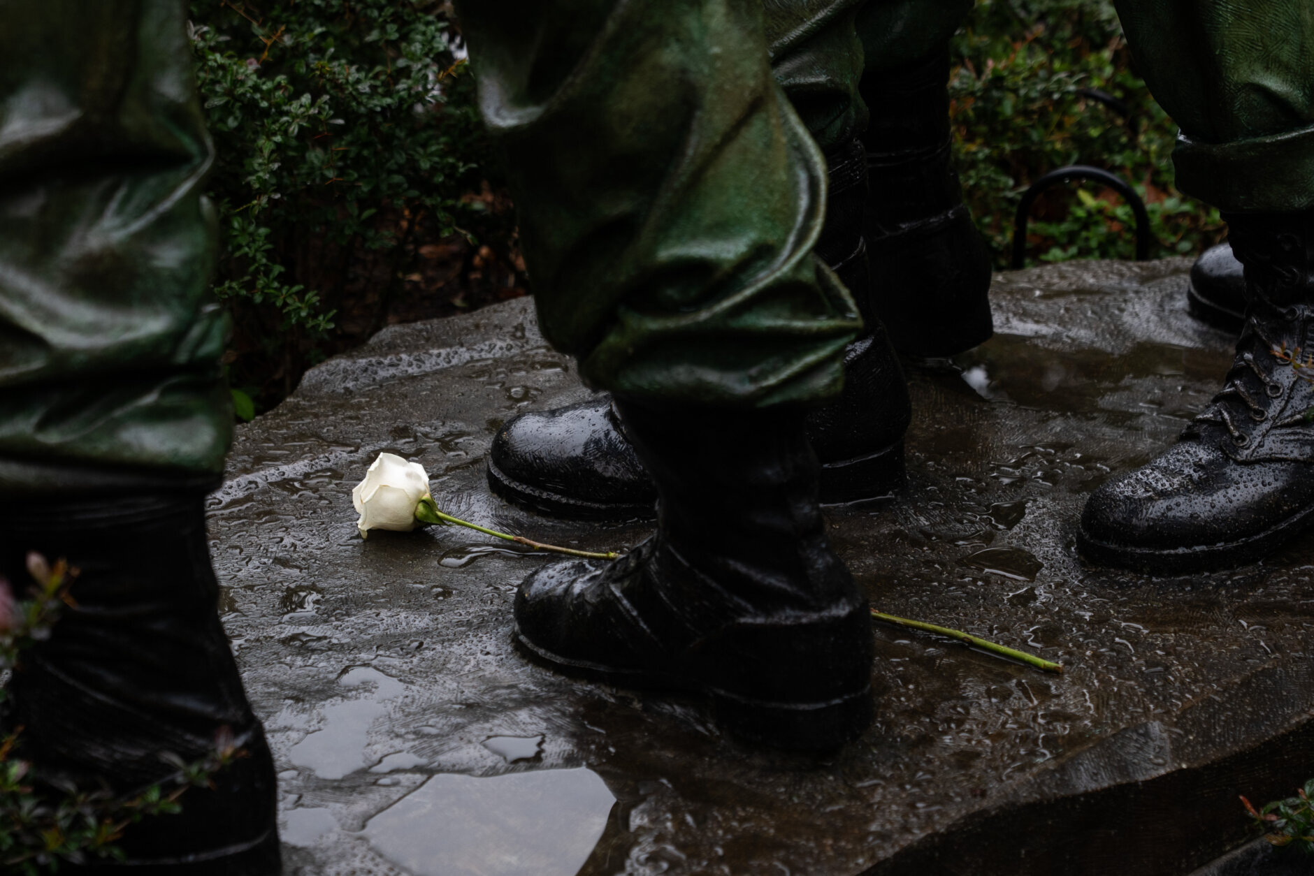 A white rose is placed at the feet of a statue at the Vietnam Veterans Memorial