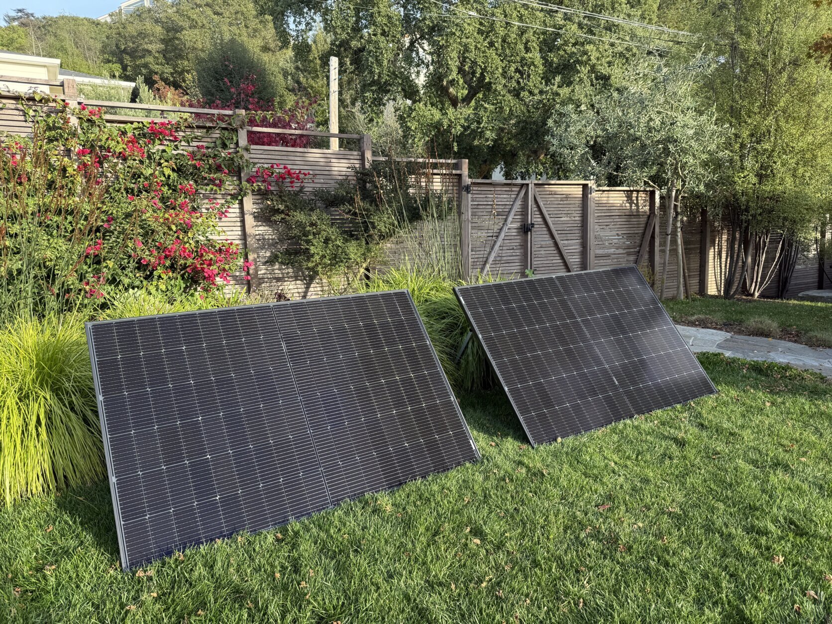 A pair of solar panels stand upright in a backyard.