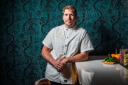 chef poses against green wall