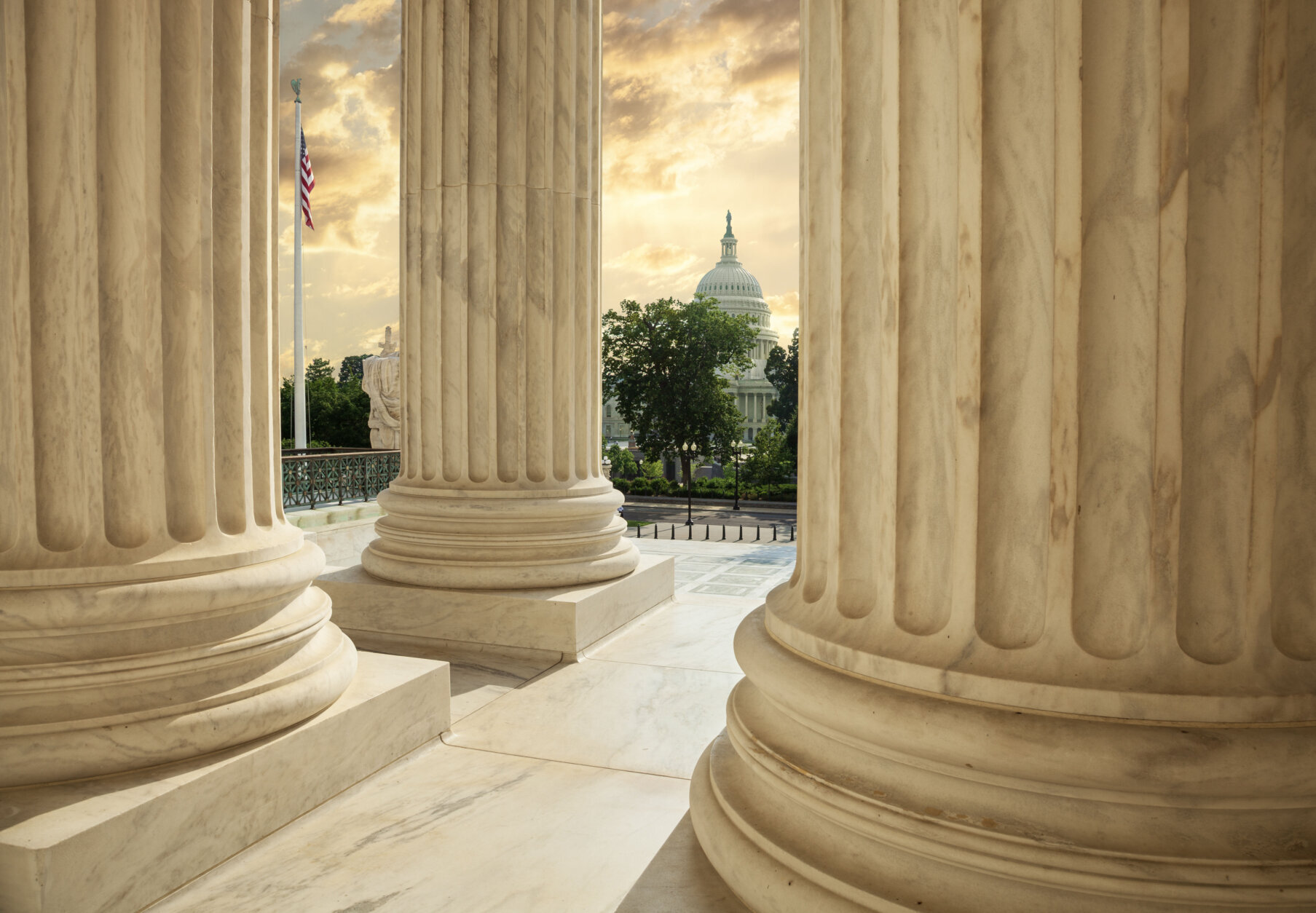 US Capitol building viewed between columns of the Supreme Court at sunset