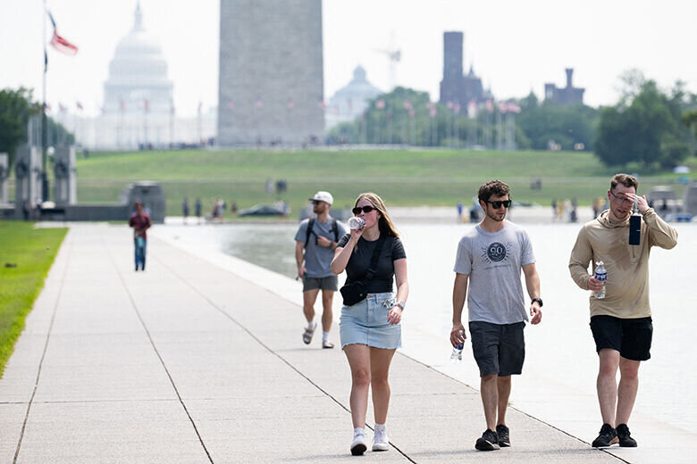 Tourists drink water as they walk along the National Mall near the Washington Monument in Washington, DC, July 25, 2025, as a heat dome sits over the region leading to extremely high temperatures. (Photo by SAUL LOEB / AFP) (Photo by SAUL LOEB/AFP via Getty Images)
