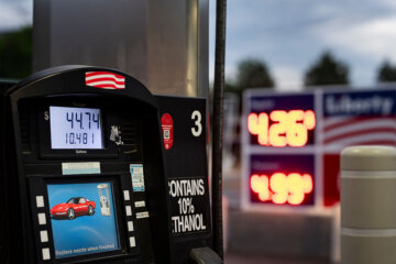 A screen displays the price of gas as unleaded gas in pumped into a vehicle at a gas station