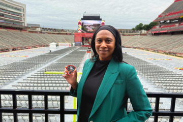 woman stands in football stadium set up for graduation ceremony